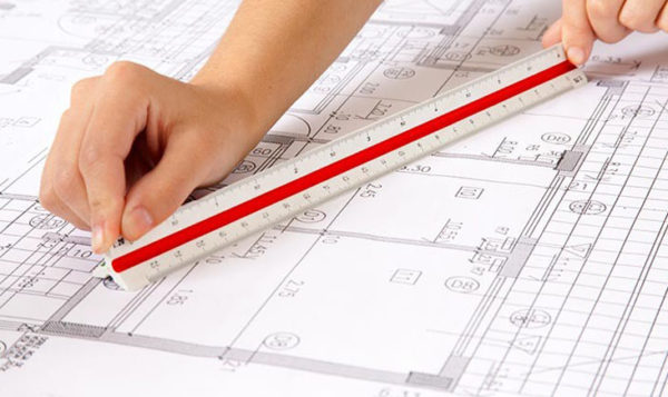 Hand holding ruler over plans for soundproofing party walls